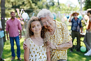 Portrait of girl with grandmother at garden party. Love and closeness between grandparent and grandchild.