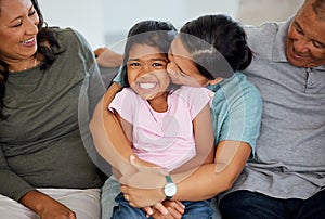 Portrait, girl with grandparents in living room as mother kiss and hug child on the sofa or couch. Latino family and