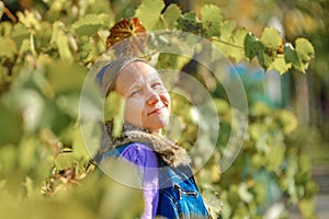 Portrait of a girl among grape leaves on a bright autumn day