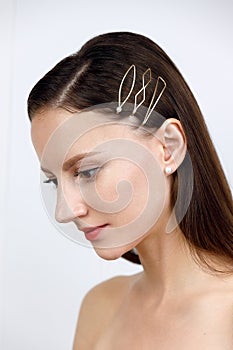 Portrait of a girl, hair parted and pinned up with golden geometric hairpins in a minimalist design, studio catalog shooting on a