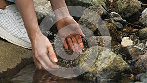 Portrait of a girl. Hands scooping water from a river in the Alpine mountains. The girl drinks clean water from the