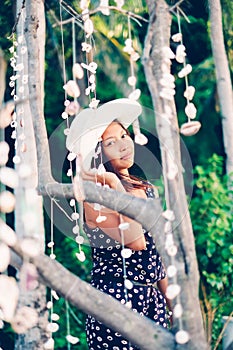 Portrait of a girl among hanging shells decoration on the beac