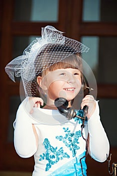 Portrait of a girl in a hat with a veil and an old retro phone in hand