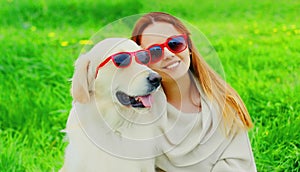 Portrait girl with her Golden Retriever dog wearing a sunglasses on green grass