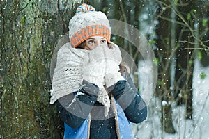 Portrait of girl hiding her face with wooly knitted bulky scarf during winter frost snowfall outdoors