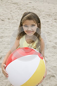 Portrait of girl holding beachball on beach smiling