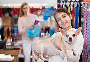 Portrait of girl holding dog during shopping at pet shop