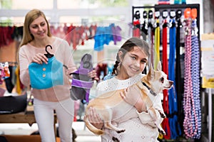 Portrait of girl holding dog during shopping at pet shop