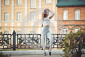 Portrait of a girl in jeans and a t-shirt on the background of the building in the evening on a summer day. street dancing in the