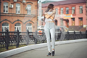 Portrait of a girl in jeans and a t-shirt on the background of the building in the evening on a summer day. street dancing in the