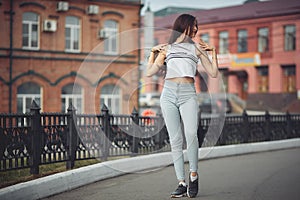 Portrait of a girl in jeans and a t-shirt on the background of the building in the evening on a summer day. street dancing in the