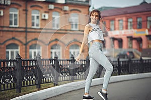 Portrait of a girl in jeans and a t-shirt on the background of the building in the evening on a summer day. street dancing in the