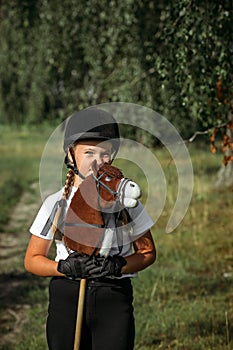 Portrait of a girl - a jockey, who holds a horse - a toy in her hands