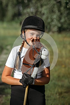 Portrait of a girl - a jockey, who holds a horse - a toy in her hands photo
