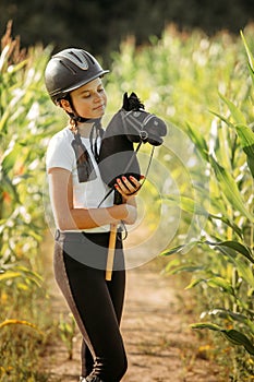 Portrait of a girl - a jockey, who holds a horse - a toy in her hands photo