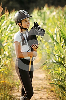 Portrait of a girl - a jockey, who holds a horse - a toy in her hands photo