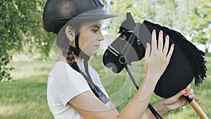 Portrait of a girl - a jockey, who strokes the mane of a horse - a toy.