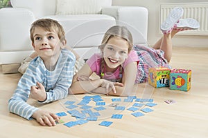 Portrait of a girl and little brother lying on floor with cards