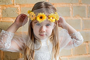 Portrait of a girl with long curly hair and a yellow flower crown in a natural setting