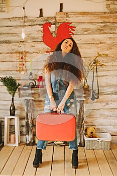 Portrait of a girl with long, curly, natural hair. Red suitcase