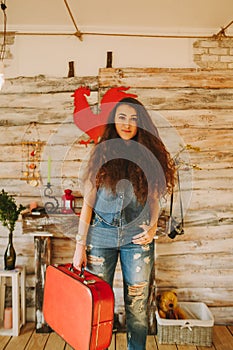 Portrait of a girl with long, curly, natural hair. Red suitcase