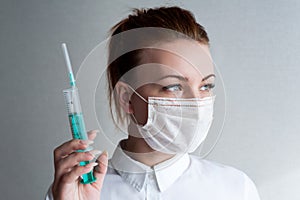 Portrait of a girl in a medical mask. Holding a syringe in her hand. Close up