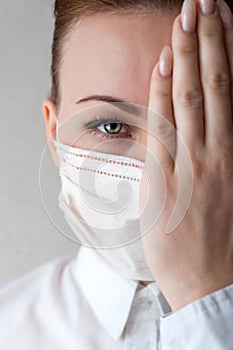 Portrait of a girl in a medical mask. I`ll cover one half of my face with my hand. Close up