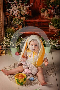 Portrait girl one year old in a bunny costume shooting in the studio in the background flowers wooden background dekor