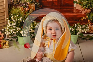Portrait girl one year old in a bunny costume shooting in the studio in the background flowers wooden background dekor photo