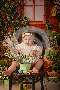 Portrait girl one year old shooting in studio sitting on wooden chair snowdrops background flowers