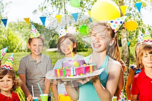 Portrait of girl in party hat holding B-day cake