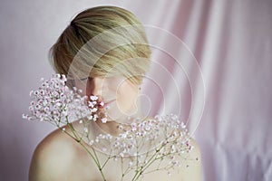 Portrait of a girl on a pink background with flowers. Tenderness and feminine. The sphere of beauty and women& x27;s