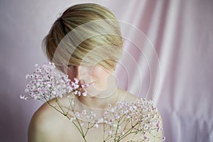 Portrait of a girl on a pink background with flowers. Tenderness and feminine. The sphere of beauty and women& x27;s