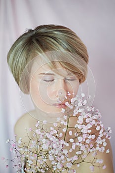 Portrait of a girl on a pink background with flowers. Tenderness and feminine. The sphere of beauty and women's