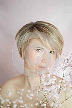 Portrait of a girl on a pink background with flowers. Tenderness and feminine. The sphere of beauty and women's