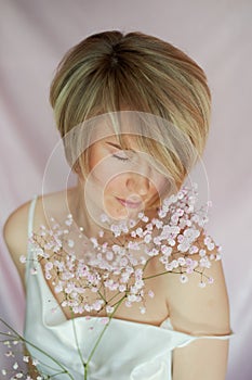 Portrait of a girl on a pink background with flowers. Tenderness and feminine. The sphere of beauty and women& x27;s