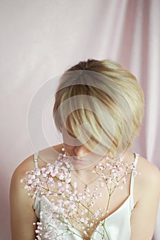 Portrait of a girl on a pink background with flowers. Tenderness and feminine. The sphere of beauty and women& x27;s