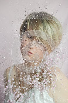 Portrait of a girl on a pink background with flowers. Tenderness and feminine. The sphere of beauty and women's