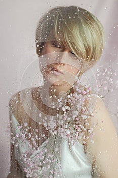 Portrait of a girl on a pink background with flowers. Tenderness and feminine. The sphere of beauty and women& x27;s