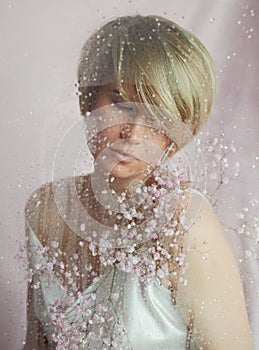 Portrait of a girl on a pink background with flowers. Tenderness and feminine. The sphere of beauty and women& x27;s