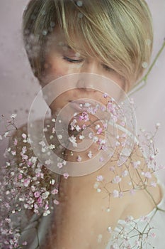 Portrait of a girl on a pink background with flowers. Tenderness and feminine. The sphere of beauty and women& x27;s