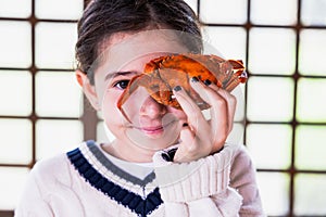 Portrait of a girl playing to hide her eyes behind a blackberry tree