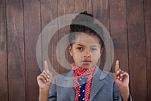 Portrait of girl pretending as businesswoman pointing upwards