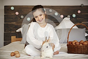 Portrait of girl with rabbit and easter basket of eggs