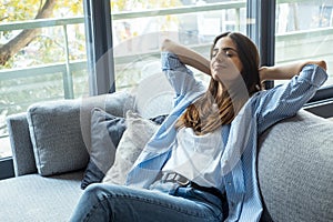 Portrait of a girl relaxing on a sofa after work at home sitting on a sofa in the living room at home. One young woman stretching