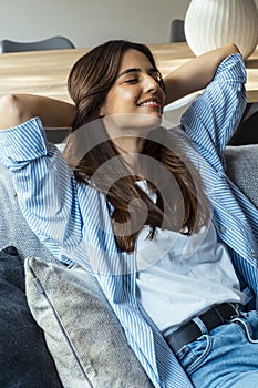 Portrait of a girl relaxing on a sofa after work at home sitting on a sofa in the living room at home. One young woman stretching
