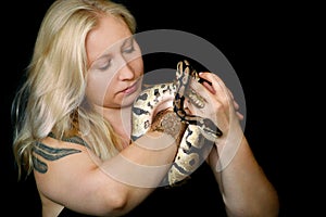 Portrait of girl with Royal Python snake. Woman holds snake in hands with beauty jewelry and posing in front of camera.