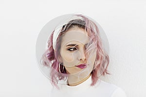 Portrait of girl with short wavy pink hair and white headband on white background