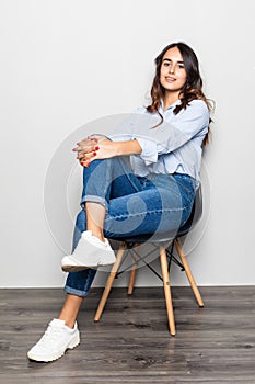 Portrait of a girl sitting on a chair over gray background