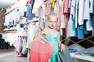 Portrait of girl standing in kids clothes store with shopping b